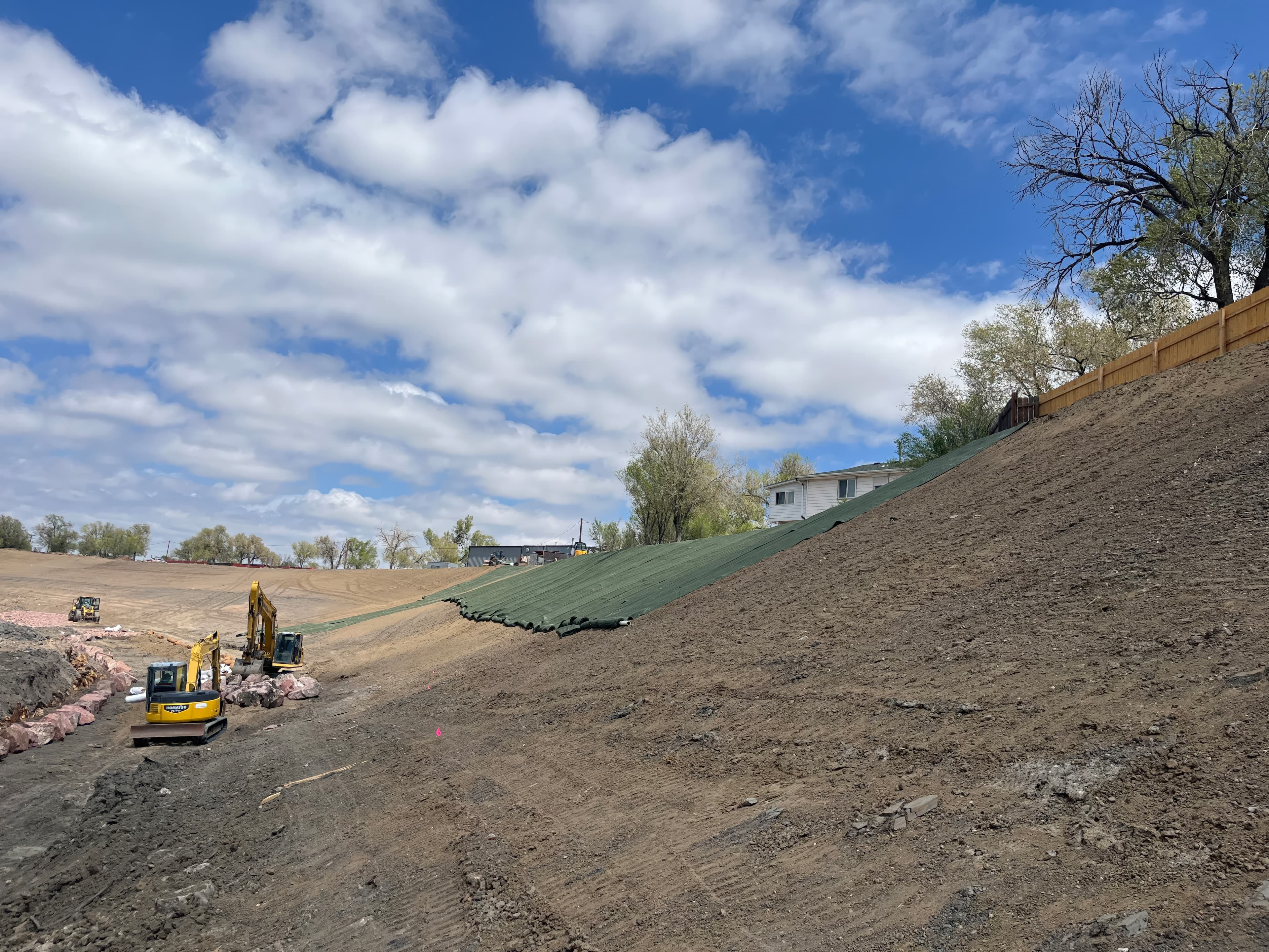 Installing MIRAGRID® XT as secondary reinforcement on steeper slope sections, providing high tensile strength and durable soil confinement in line with EBGEO design principles.